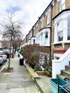a street with houses and a cat sitting on the sidewalk at London Townhouse 1-Bed Apartment with Garden in Tufnell Park near Emirates Stadium and 10 mins to Kings Cross in London