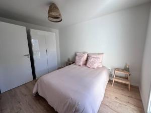 - une chambre blanche avec un lit et des oreillers roses dans l'établissement Neuf-Lumineux-Calme à 20 mn de Paris, à Romainville