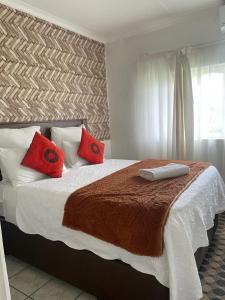 a bedroom with a large bed with red pillows at Dwengu Guest house in Margate