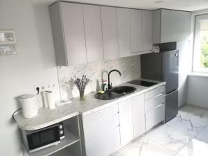 a white kitchen with a sink and a microwave at Plungės gatvės 18 apartamentai in Telšiai