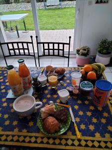 una mesa con alimentos para el desayuno y naranjas en ella en Sous le pommier, en Douvres-la-Délivrande