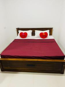 Una cama con dos almohadas de corazón rojas. en Villa Arshu., en Bentota
