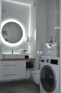 een witte badkamer met een wasmachine en een spiegel bij Apart city break apartament in Świebodzice