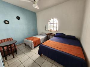 een slaapkamer met 2 bedden, een tafel en een raam bij Casa Marina in Puerto Vallarta
