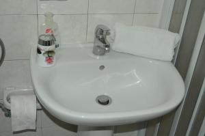 un lavabo blanco con un dispensador de jabón. en Bed and Breakfast Vecchio Porto, en Catania