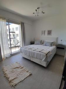 Dormitorio blanco con cama y ventana grande en Elegancia y Confort G&A Rent (308) en Ezeiza