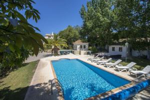 - une piscine avec des chaises longues à côté d'une maison dans l'établissement Villa Caravela, à Almancil