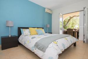 - une chambre avec un grand lit aux murs bleus dans l'établissement Villa Caravela, à Almancil