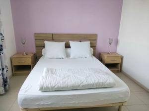 um quarto com uma cama branca com duas mesas de cabeceira em Maison Cosy à proximité de la Plage em Hermanville-sur-Mer