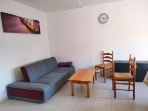 uma sala de estar com um sofá, uma mesa e cadeiras em Maison Cosy à proximité de la Plage em Hermanville-sur-Mer
