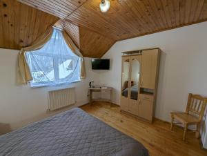 um quarto com uma cama, uma janela e uma cadeira em Oskolok Dovbusha Mini-Hotel em Yaremche