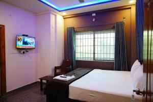 um quarto de hotel com uma cama e uma televisão em LEE PARADISE INN em Bangalore