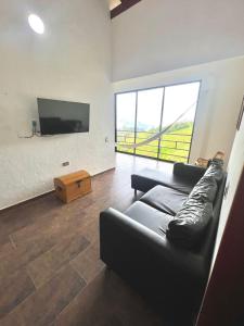 een woonkamer met een zwarte bank en een flatscreen-tv bij Orquideas 3 in Jericó