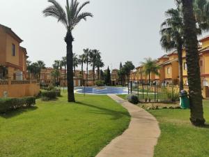 einen Weg durch einen Park mit Palmen und Häusern in der Unterkunft Chalet Islantilla "Costa de la Luz" in Lepe