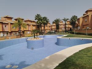 ein großer Pool mit einer Palme in der Mitte in der Unterkunft Chalet Islantilla "Costa de la Luz" in Lepe