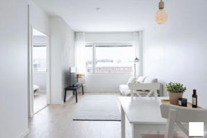 Moderni kaksio ydinkeskustassa في كوبيو: غرفة معيشة بيضاء مع أريكة وطاولة