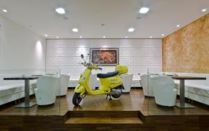 uma scooter amarela numa sala de jantar com mesas e cadeiras em El Patio Hotel em Corciano