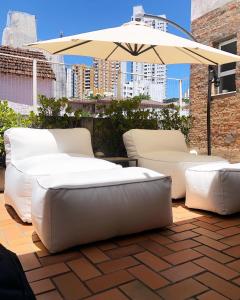two white couches and an umbrella on a patio at Viver Bahia Pousada in Salvador