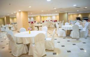 um salão de banquetes com mesas brancas e cadeiras brancas em فندق إي دبليو جي العزيزية em Meca