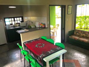 cocina con mesa con sillas verdes y encimera en Chalé Azul en Tamandaré