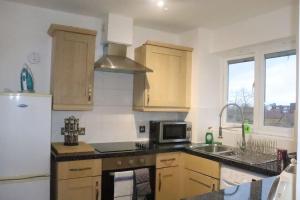 a kitchen with wooden cabinets and a sink and a microwave at Snug 2BR Apt. Free Parking, 4KTV in London