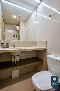 La salle de bains est pourvue de toilettes, d'un lavabo et d'un miroir. dans l'établissement Mar & Conforto: Seu lar em Salvador, à Salvador