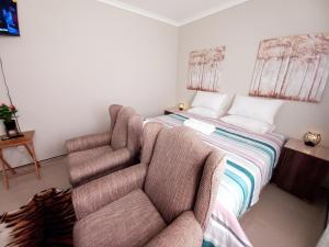 a bedroom with a bed with a couch and a chair at TALITHA'S SELF-CATERING ACCOMONDATION in Walvis Bay