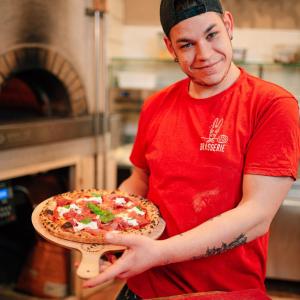 アドリアにあるLocanda del Musso con Ristoranteの窯前でピザを握る男
