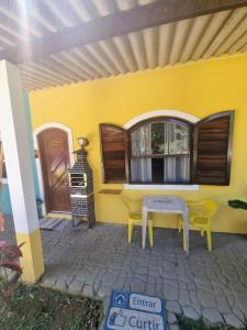 Itariri的住宿－Pousada_tres_amores，天井上的黄色房屋,配有桌椅