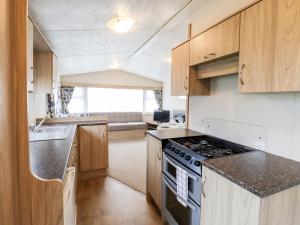 a kitchen with wooden cabinets and a stove top oven at 24 Winchelsea Sands Holiday Park in Winchelsea