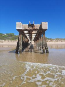 a pier sitting in the water on a beach at Britsies @ Sea in Mossel Bay
