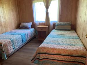 Habitación pequeña con 2 camas y ventana en Cabaña Llonquén en Liquiñe