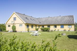 a large yellow house with two white chairs in the yard at Bruksparkens Hostel in Vellinge