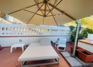 - une table et des chaises blanches sous un parasol sur la terrasse dans l'établissement Ti racconto il mare, à Salerne