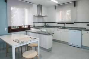 a kitchen with white cabinets and a table and stools at La Solana-Vivienda de uso turístico in Baños de Río Tobía