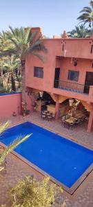 a large house with a blue pool in front of it at Maison Vallée Du Ziz in Oulad Aïssa