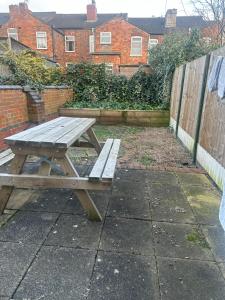 un tavolo da picnic in legno su un marciapiede accanto a una recinzione di Party house a Derby