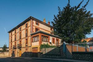 a large brick building with a tree in front of it at Apartamento Turistico la Solana in Baños de Río Tobía