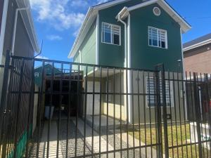 una casa verde con una valla delante en Casas Cartes en Valdivia