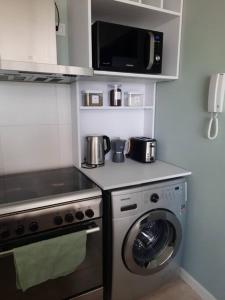 a kitchen with a washing machine and a microwave at Diseño Exclusivo, Parking y Vistas al Valle in Neuquén