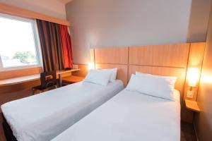 a hotel room with two beds and a window at ibis Presidente Prudente Manoel Goulart in Presidente Prudente