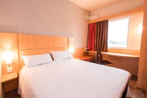 a hotel room with a large bed and a window at ibis Presidente Prudente Manoel Goulart in Presidente Prudente