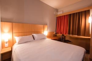 a bedroom with a white bed and a red curtain at ibis Presidente Prudente Manoel Goulart in Presidente Prudente