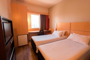 a hotel room with two beds and a television at ibis Presidente Prudente Manoel Goulart in Presidente Prudente
