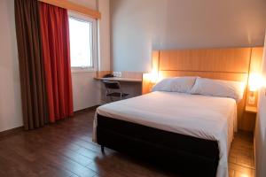 a hotel room with a bed and a desk and a window at ibis Presidente Prudente Manoel Goulart in Presidente Prudente