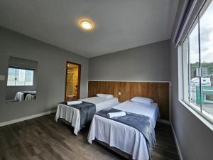 um quarto de hotel com duas camas e uma janela em Residenz100 em Blumenau