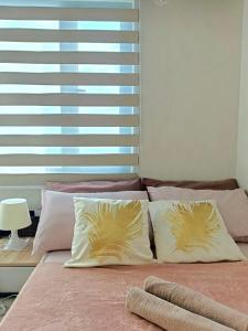 a bed with two pillows on it with a window at Grass Residences by Team A in Manila