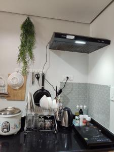 a kitchen counter with a dish rack with pots and pans at Grass Residences by Team A in Manila