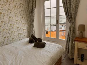 a teddy bear sitting on a bed with a window at Compton House 1, Sea & Castle Views in Conwy
