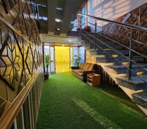 einen Flur mit grünem Teppich und Treppe in einem Gebäude in der Unterkunft Behtereen resort in Srinagar